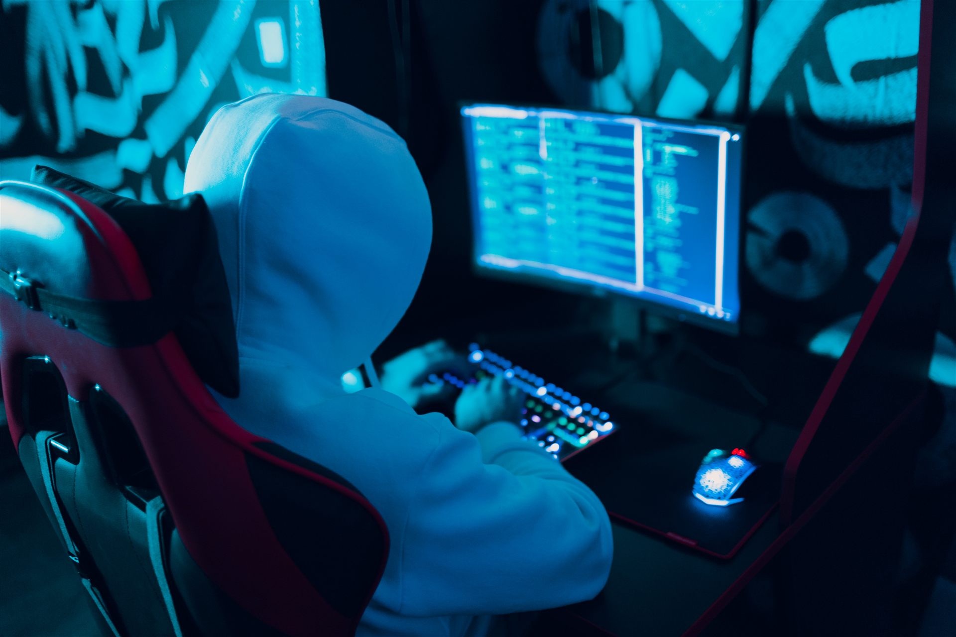 Hooded figure typing code in a dark room